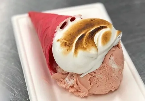 A pink-colored cone ice-cream topped with marshmallow